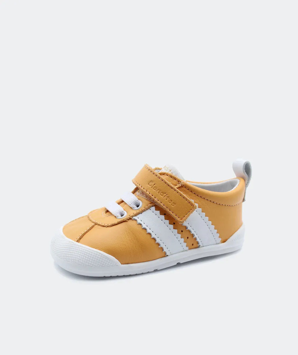 Sapatilha Blanditos Iris cor naranja (amarelo mostarda/branco) vista de lado. Calçado Barefoot Respeitador com sola zero drop e velcro.