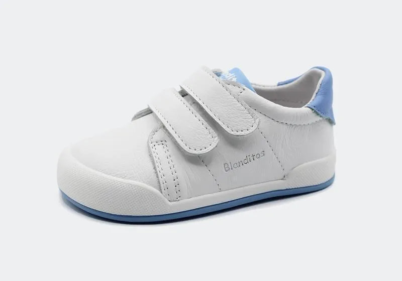 Sapatilha Blanditos Londres 2025 branca com sola e detalhe no calcanhar azuis. Vista lateral. Calçado Respeitador barefoot para criança. Calçado Barefoot com fecho de velcro.