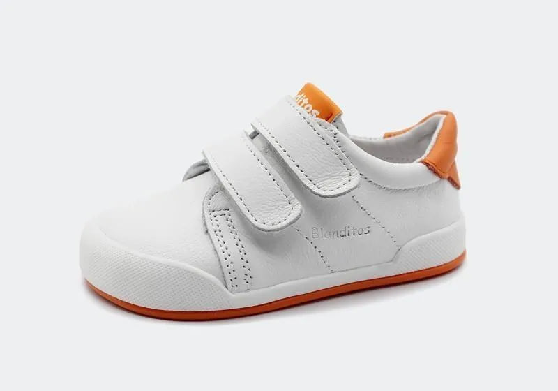 Vista lateral da sapatilha Blanditos Londres 2025 branca, com pormenores em laranja na sola e calcanhar. Calçado Barefoot e Respeitador para criança. Velcro duplo.