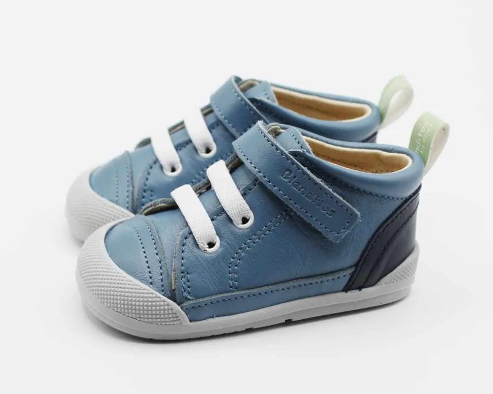Par de sapatilhas barefoot Blanditos Luigi Azafata azuis para criança. Calçado respeitador em pele com atacadores elásticos brancos, velcro, biqueira reforçada cinza e sola flexível cinza. Vista lateral. Calçado Barefoot infantil de meia-bota.