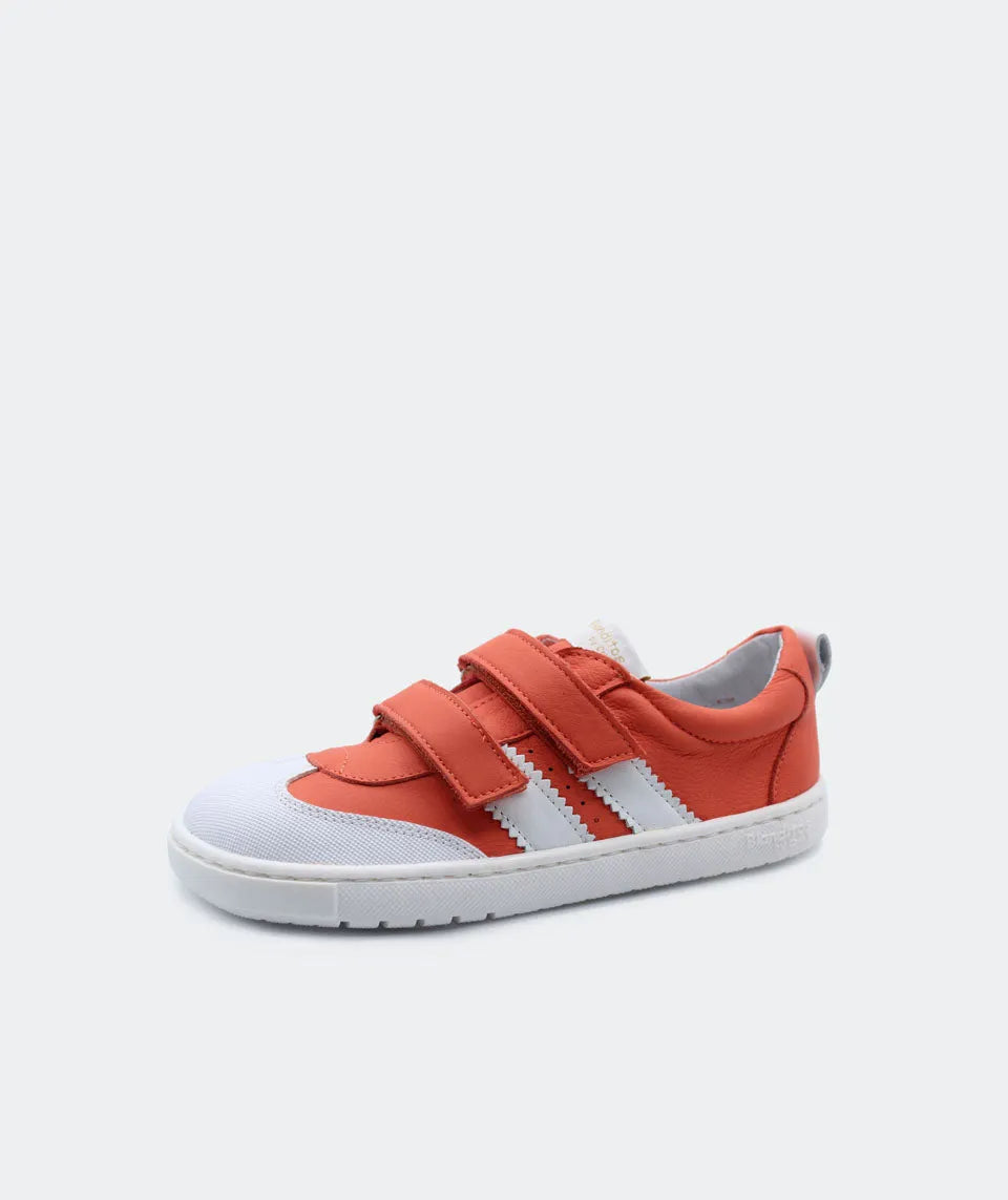 Vista lateral das sapatilhas Blanditos Marea Laranja (ou Coral), calçado respeitador infantil com base branca, detalhes e velcro em laranja/coral vivo e risca lateral branca. Calçado Barefoot.