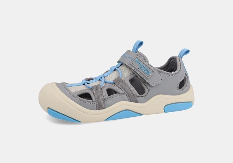 Sandália desportiva barefoot para criança da Blanditos by Crio's, modelo Olimpo Gris, em tons de cinzento, bege e azul, com fecho de velcro e biqueira reforçada.