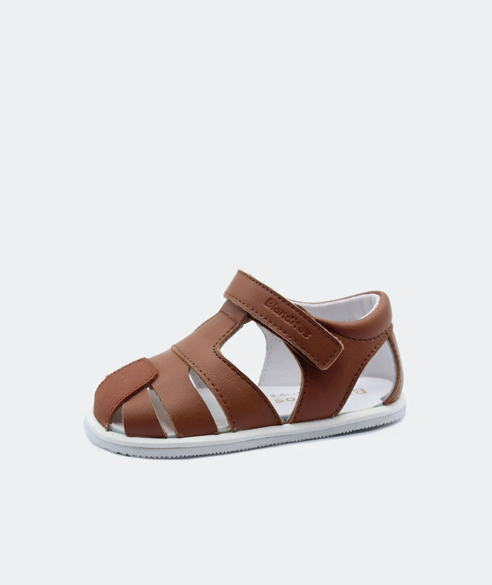Sandálias Abertas Blanditos by Crio´s Isla Cuero em couro castanho com sola branca e fecho de velcro, oferecendo um design flexível e respeitador dos pés infantis.