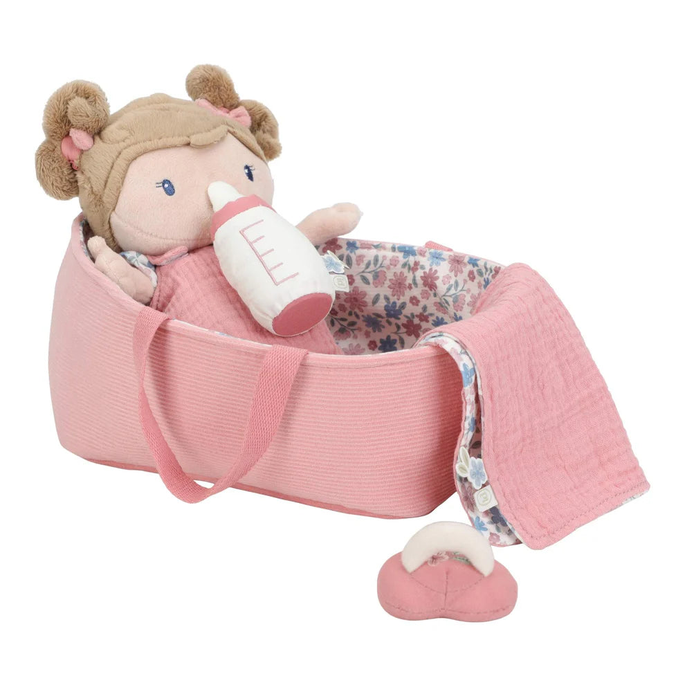 Boneca Bebé Rosa a ser alimentada com o biberão dentro da sua cesta, com a manta e a chupeta ao lado.