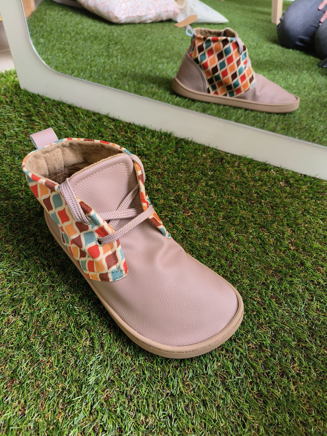 Bota barefoot Blanditos, em tom bege com padrão geométrico colorido na parte superior. Design flexível, leve e de sola fina, proporcionando liberdade de movimento e desenvolvimento saudável dos pés. Ideal para um calçado respeitador, confortável e adequado ao dia a dia.

