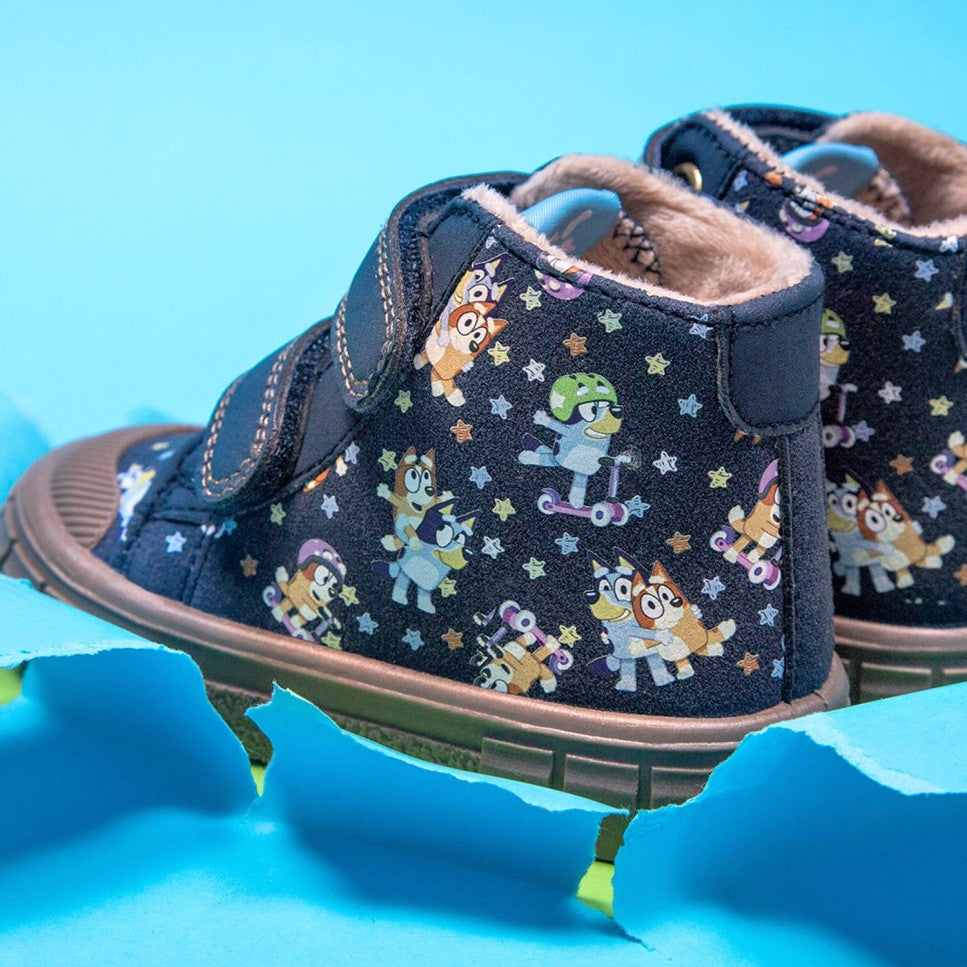 Detalhe das botas Garvalín Bluey e Bingo Azul, mostrando o estampado dos personagens em ação e o forro quentinho, sobre um fundo azul vibrante.