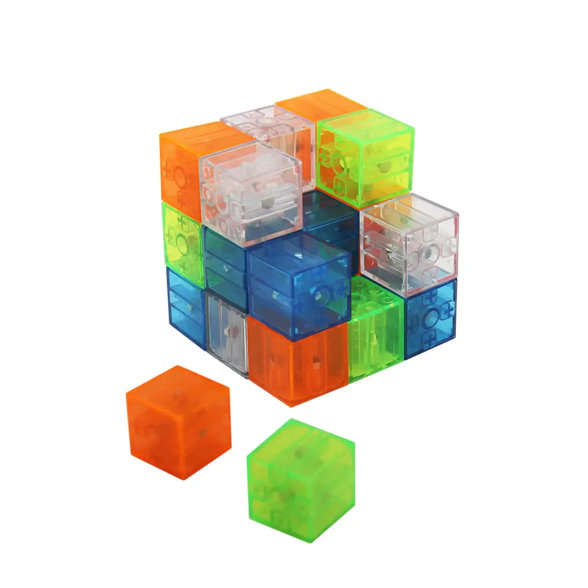 Detalhe de cubos magnéticos IMACUBIX translúcidos e coloridos (laranja, azul, verde) a formar um cubo maior, com duas peças soltas em primeiro plano.