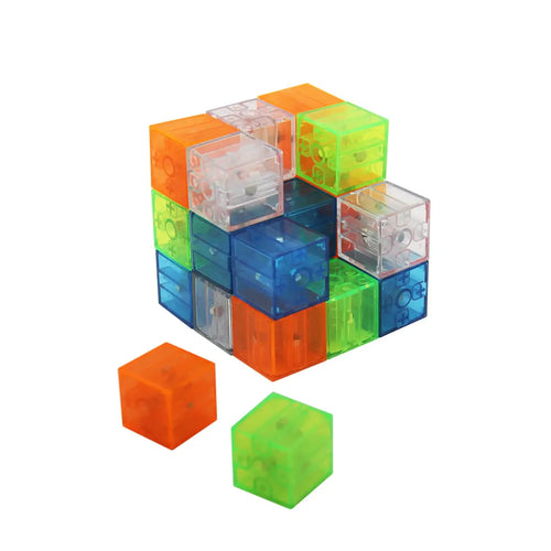 Detalhe de cubos magnéticos IMACUBIX translúcidos e coloridos (laranja, azul, verde) a formar um cubo maior, com duas peças soltas em primeiro plano.