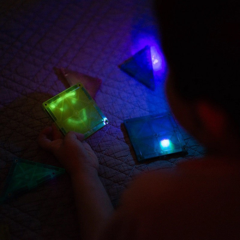 Criança brincando com blocos magnéticos IMANIX que brilham no escuro. Jogo educativo para estimular a criatividade.