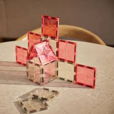 Estrutura construída com telhas magnéticas transparentes e cor-de-rosa, exibindo um design de casa ou torre.