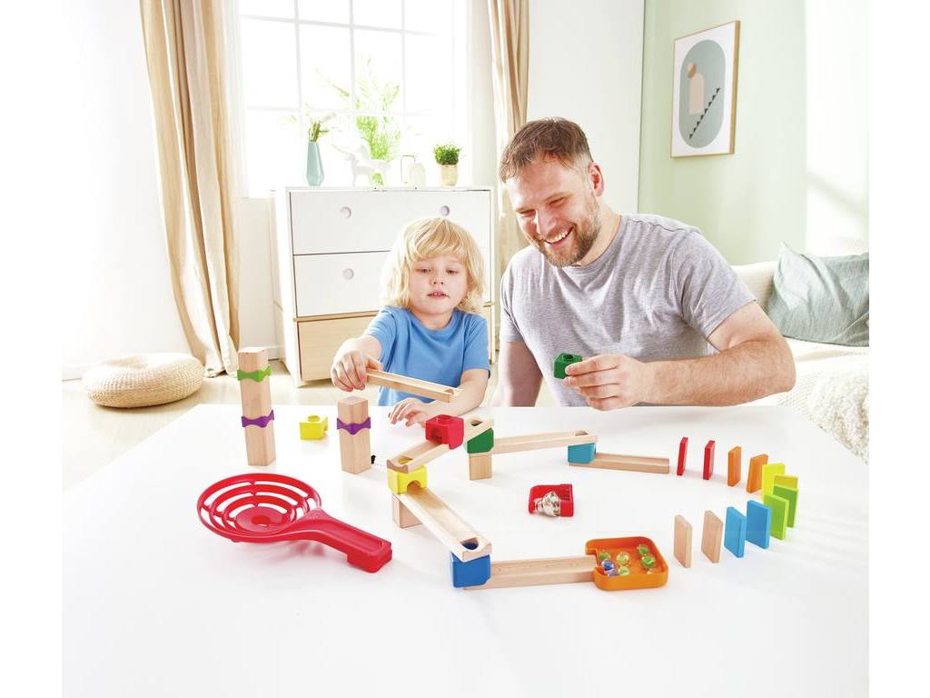 Pai e filho a construírem uma pista de esferas de madeira com dominós. Brinquedos de construção e raciocínio lógico para jogar em família.