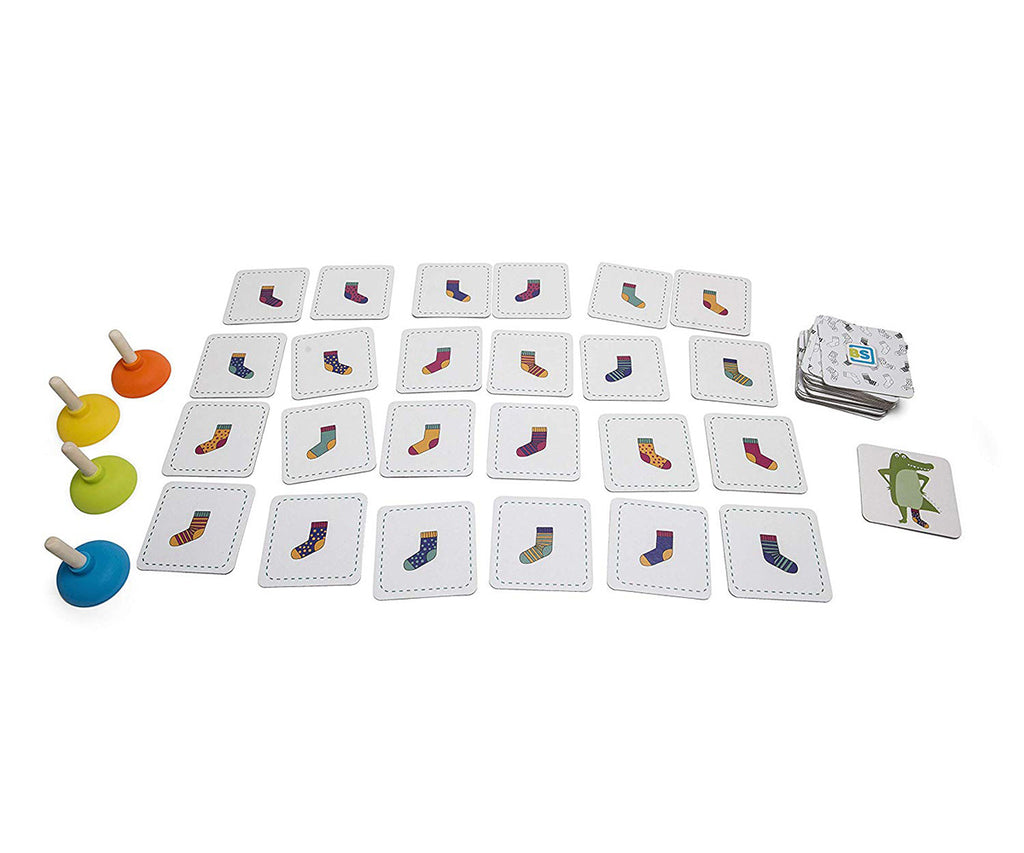 Componentes do "Jogo das meias de crocodilos" espalhados: cartões de meias coloridas, cartas de crocodilo e quatro ventosas de cores vivas.