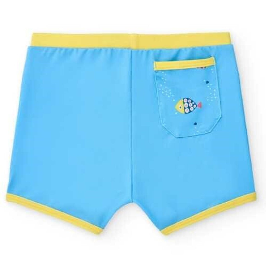Boxer de praia infantil BtBox azul-claro com cós e bainhas amarelas, mostrando o bolso traseiro com um peixe amarelo decorativo.