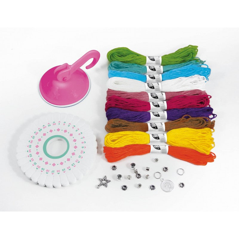 Conteúdo do kit Buki Be Teens, mostrando os fios de algodão, a roda de entrelaçamento, a ventosa e os acessórios metálicos (contas e pendentes).