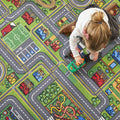 Criança pequena a brincar com um carrinho verde sobre o tapete de brincar Buki City, mostrando o design detalhado das estradas e áreas verdes.