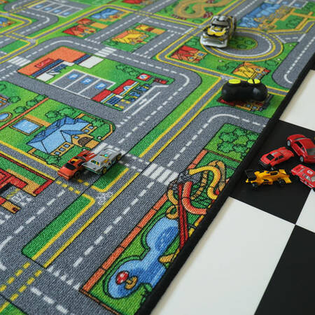 Detalhe do tapete de brincar Buki City com vários carrinhos em miniatura e a representação de um parque de estacionamento e uma zona de diversão.