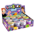 Caixa expositora de ponto de venda (PDV) com o logótipo "Sensory Slime" da Buki, exibindo vários boiões de slime e indicando a idade mínima de 6+.
