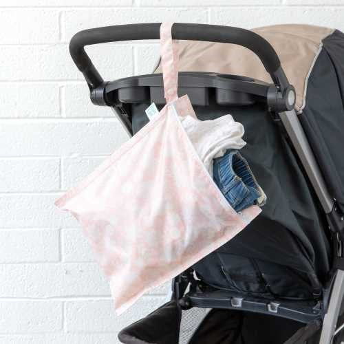 Bolsa impermeável Bumkins pendurada no puxador de um carrinho de bebé, com roupa suja ou molhada visível no interior.
