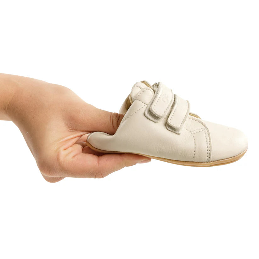 Mão a segurar a sapatilha 'Coala' Bunny Barefoot rosa perolado, demonstrando a leveza e o formato adaptável do calçado.