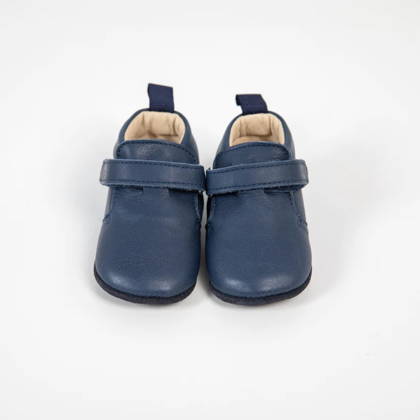 Close-up frontal dos sapatinhos bebé Bunny Barefoot Girafinha em pele azul marinho, realçando a textura da pele e o fecho de velcro ajustável.