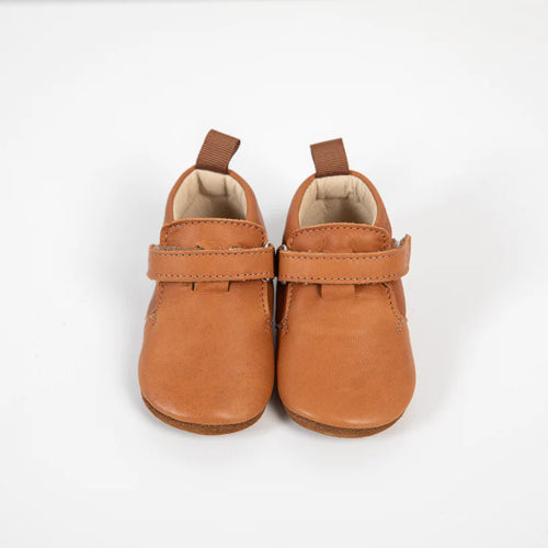 Vista frontal de um par de sapatinhos Barefoot Girafinha camel em pele suave, mostrando o fecho de velcro e a construção flexível.