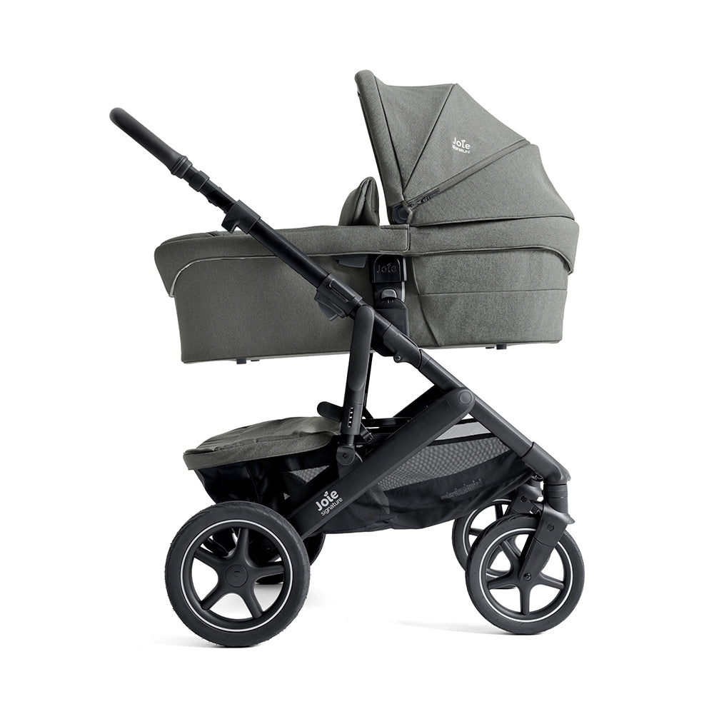 Detalhe da asa de transporte em couro sintético envelhecido da alcofa Joie Ramble XL, mostrando a qualidade dos acabamentos.