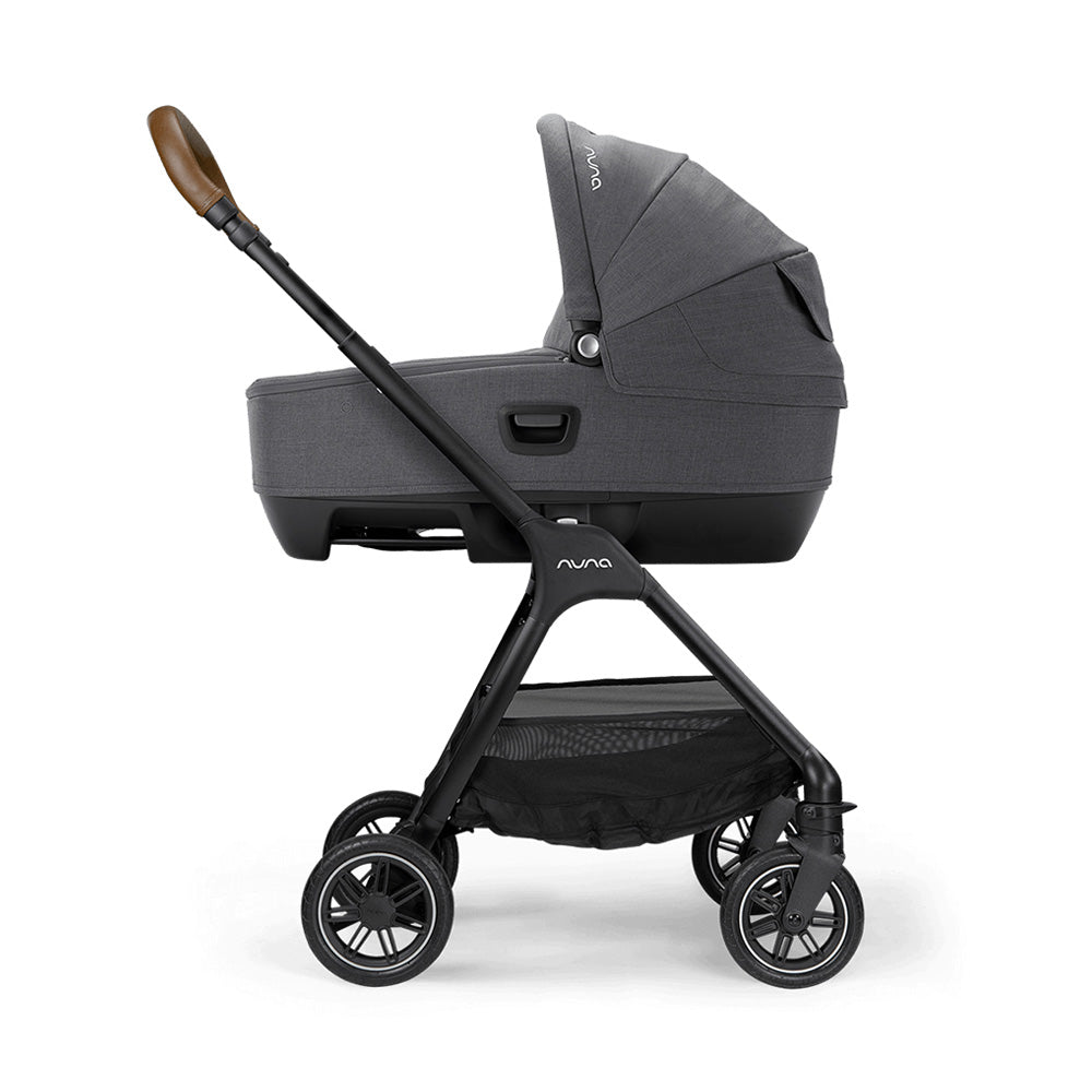 Alcofa Nuna Cari Next cinzenta montada num carrinho de passeio Nuna, vista lateral completa com cesto de arrumação inferior.