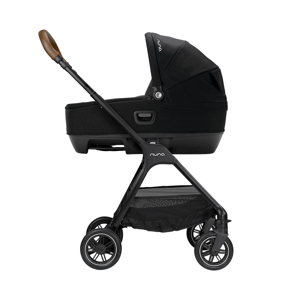 Alcofa Nuna Cari Next preta acoplada a um chassis de carrinho de passeio, mostrando o sistema modular completo com pega em pele castanha.