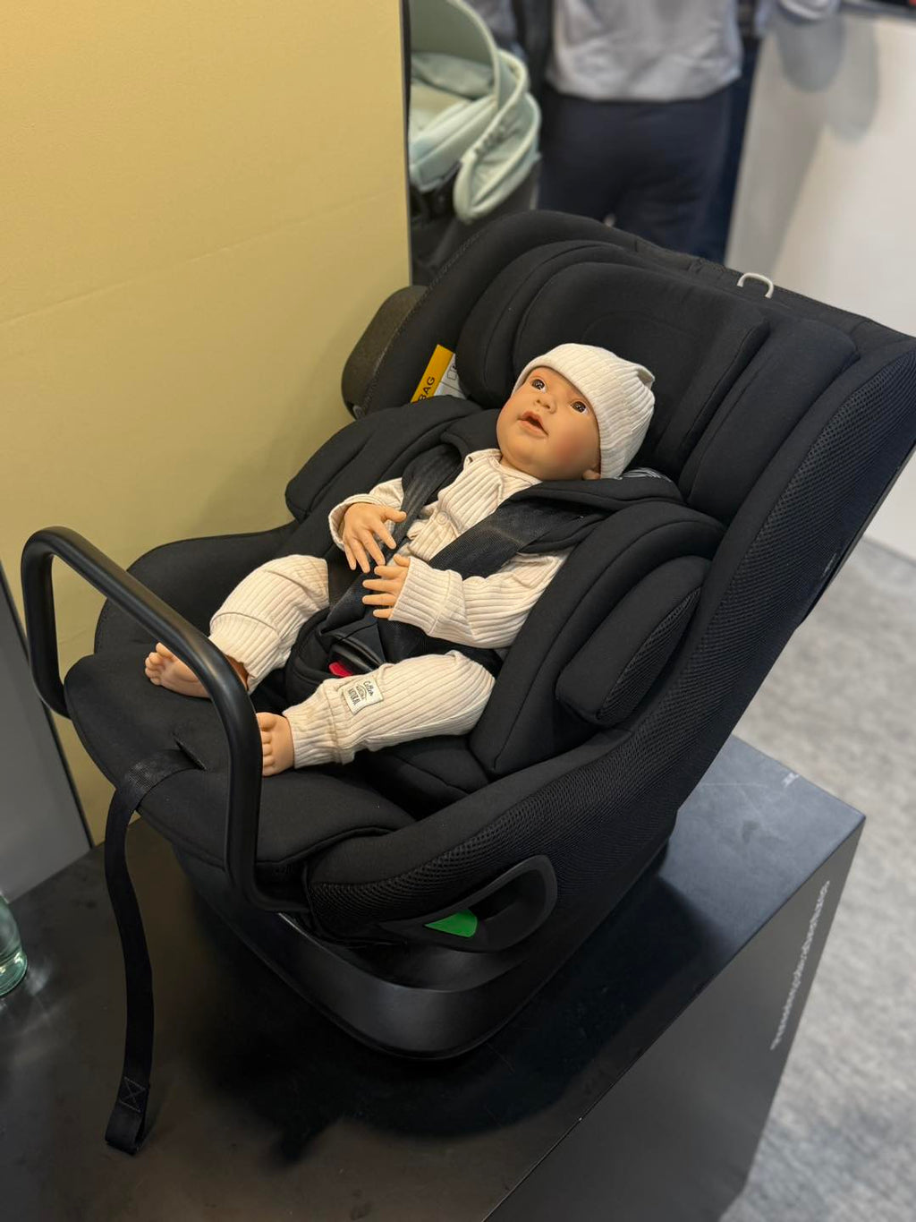Cadeira auto AXKID Minikid CORE preta com um boneco bebé deitado, demonstrando a posição de recém-nascido.