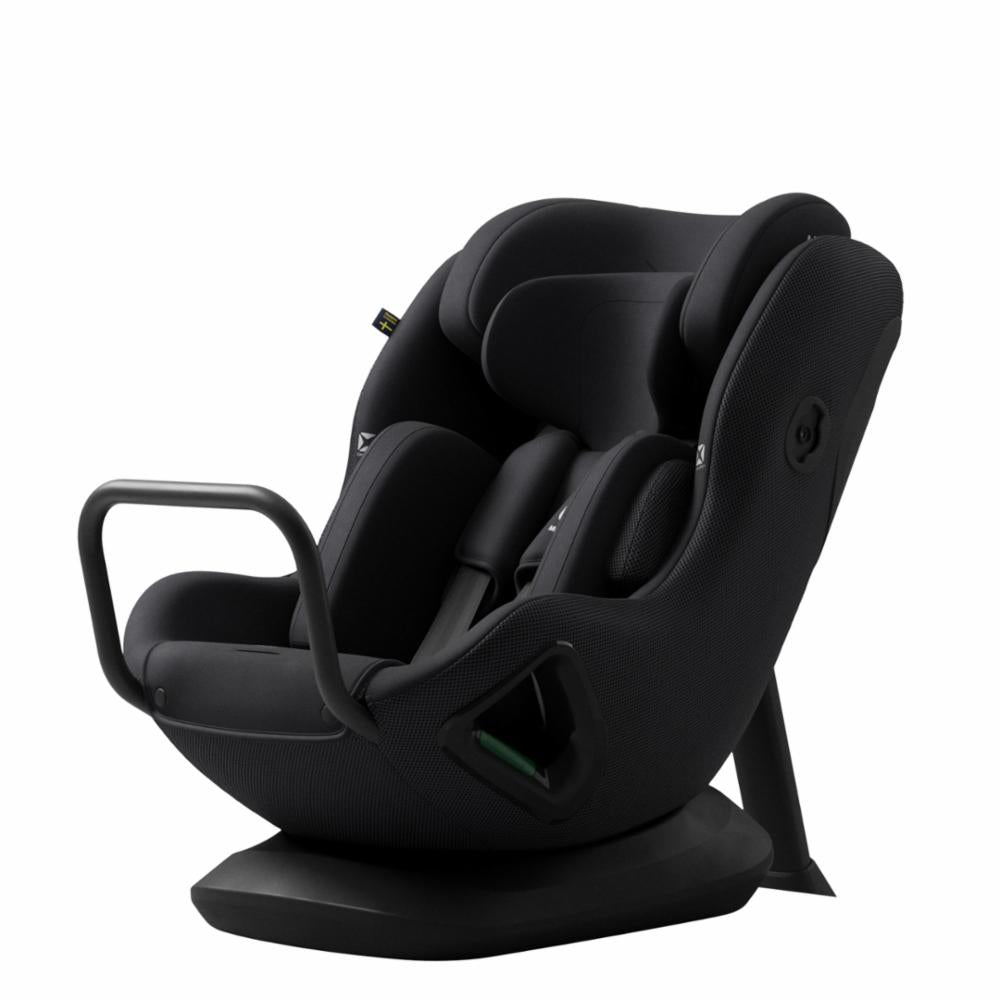 Cadeira auto AXKID Minikid CORE preta, ligeiramente inclinada, mostrando o design ergonómico e a barra de apoio frontal.