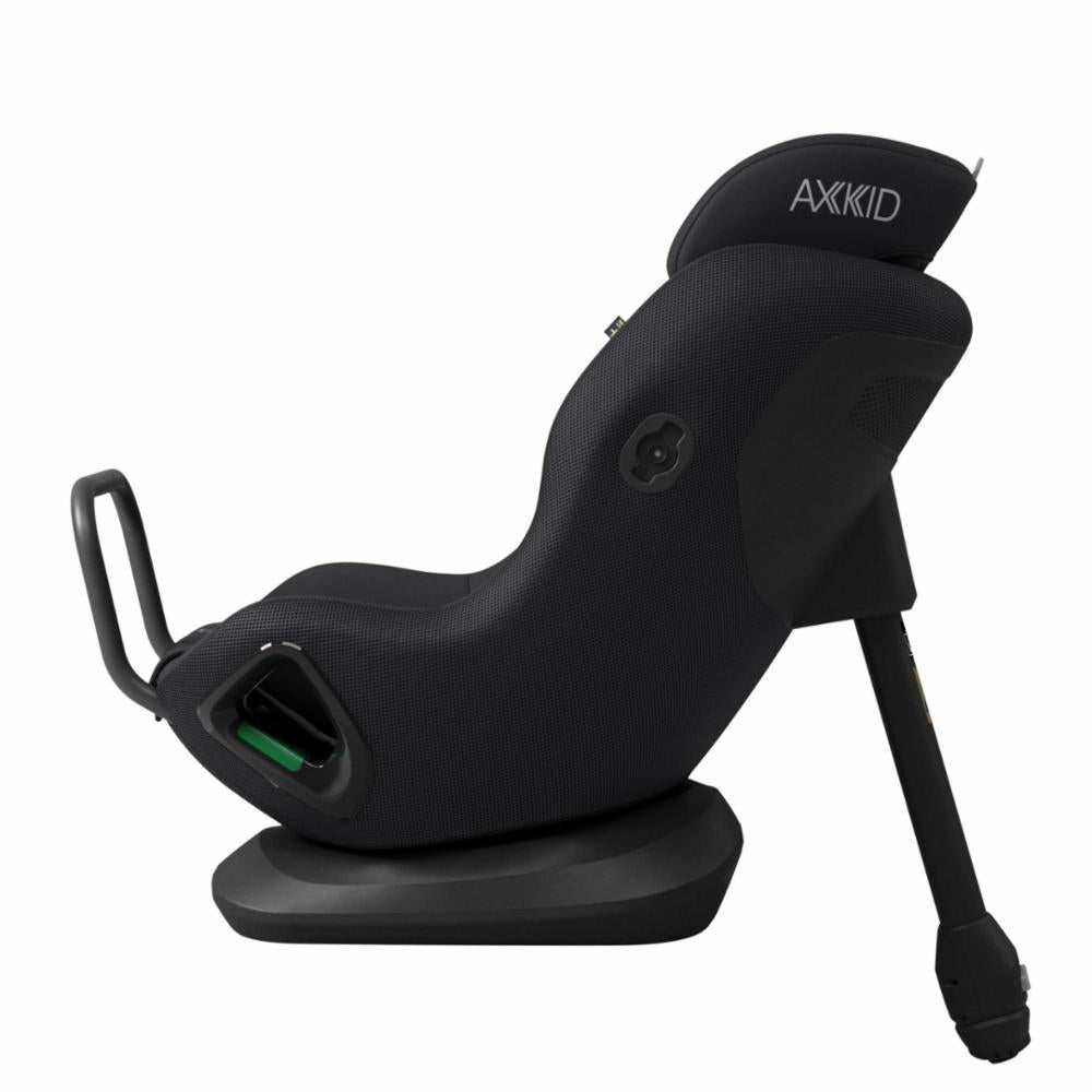 Cadeira auto AXKID Minikid CORE preta, vista de perfil, mostrando a inclinação para trás e a perna de apoio estendida.