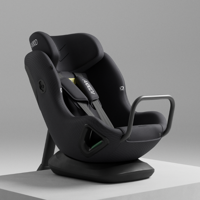 Cadeira auto AXKID Minikid CORE preta, em estúdio, sobre uma superfície branca, com iluminação profissional.