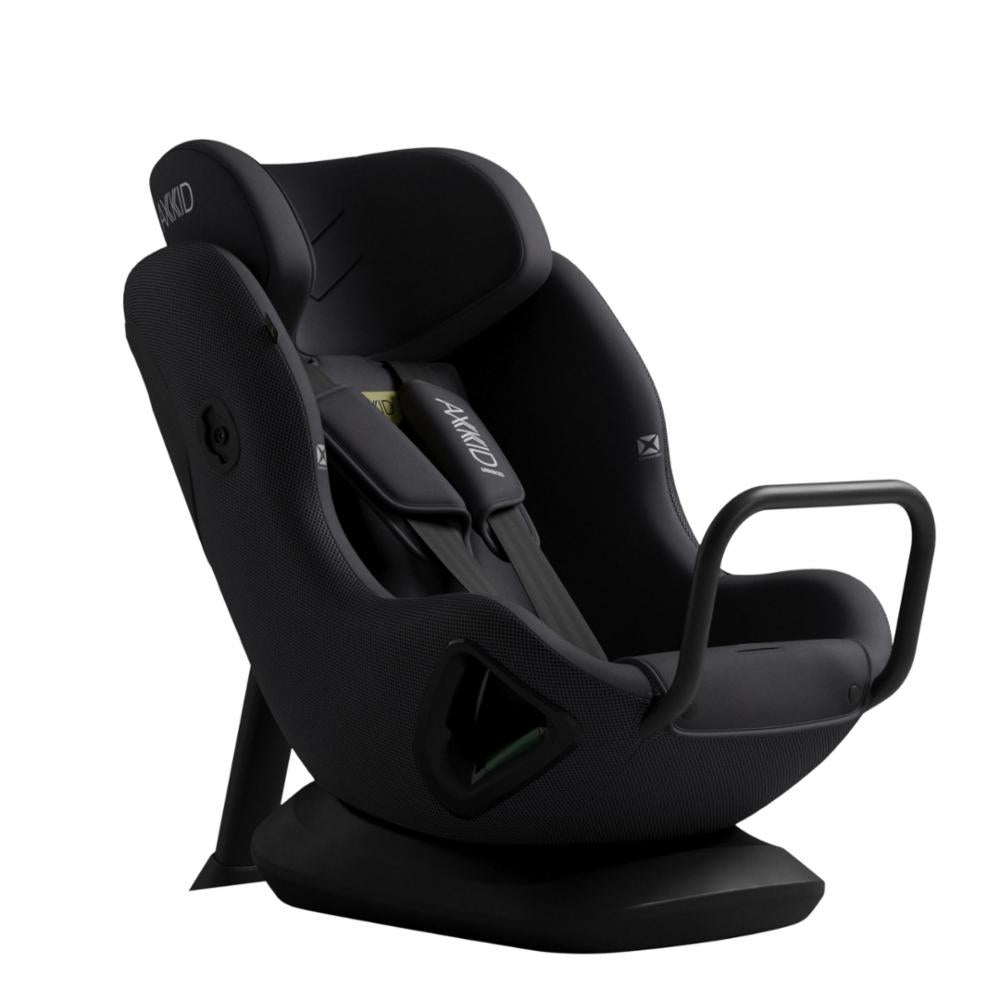 Cadeira auto AXKID Minikid CORE preta, vista de ângulo frontal-lateral, destacando a base de instalação e o apoio de cabeça.
