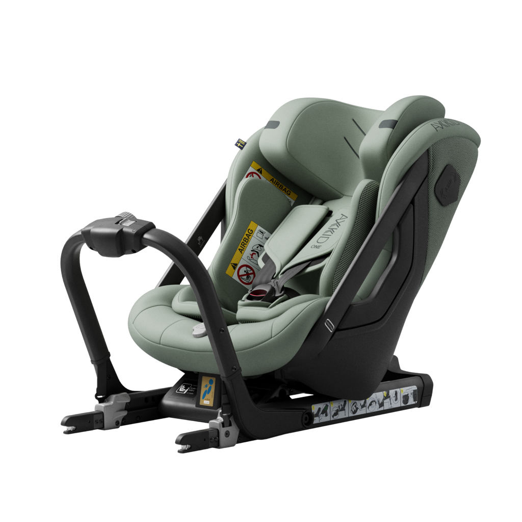 Cadeira auto Axkid ONE 3 verde-sálvia, instalada contra a marcha, com base ISOFIX e arnês, isolada em fundo preto.