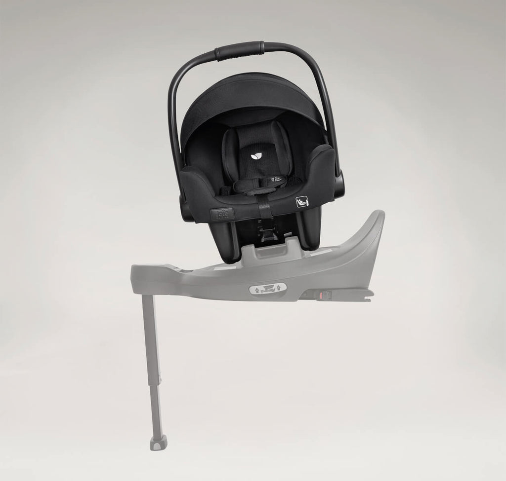 Cadeira auto ovo Joie i-Starter encaixada numa base de carro cinzenta (i-Base Encore), com o pé de apoio estendido no chão.