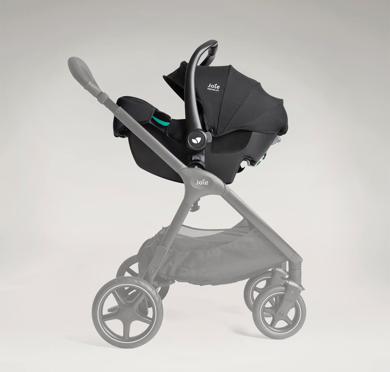 Cadeira auto ovo Joie i-Starter preta acoplada ao chassis de um carrinho de bebé cinzento, pronta para uso em sistema de viagem (travel system).