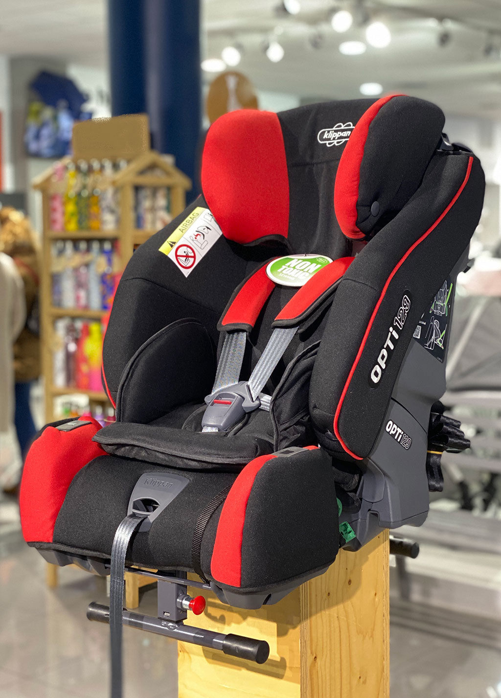 Vista lateral da cadeira auto Klippan Opti129 mostrando o apoio de cabeça ajustável e o assento profundo em tecido preto.