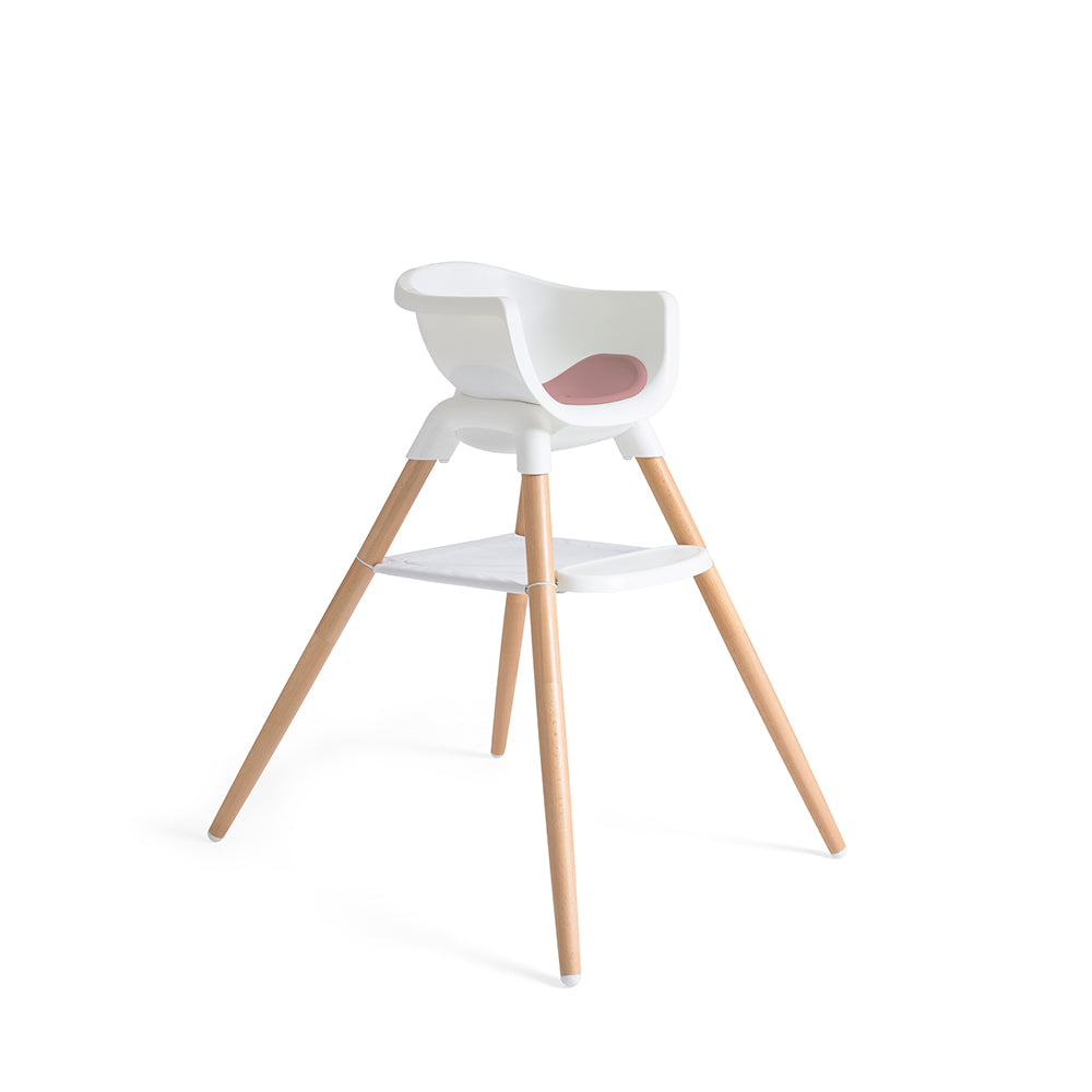 Cadeira de refeição Joie Chestnut em modo alto, vista lateral. Estrutura branca com pernas em madeira de faia e apoio inferior.