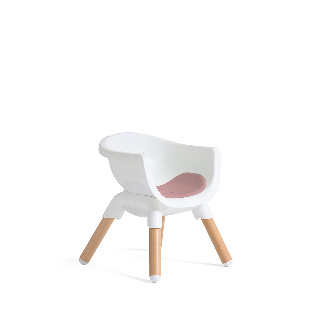 Cadeira evolutiva Joie Chestnut em modo júnior baixa, vista ligeiramente angular. Assento branco com almofada rosa e pernas de madeira curtas.