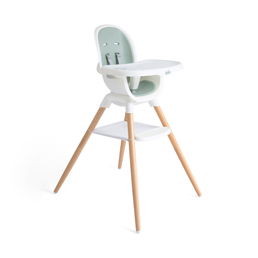 Cadeira de refeição Joie Chestnut em modo cadeira alta, com assento branco e verde-água, e pernas em madeira de faia. Vista em ângulo.