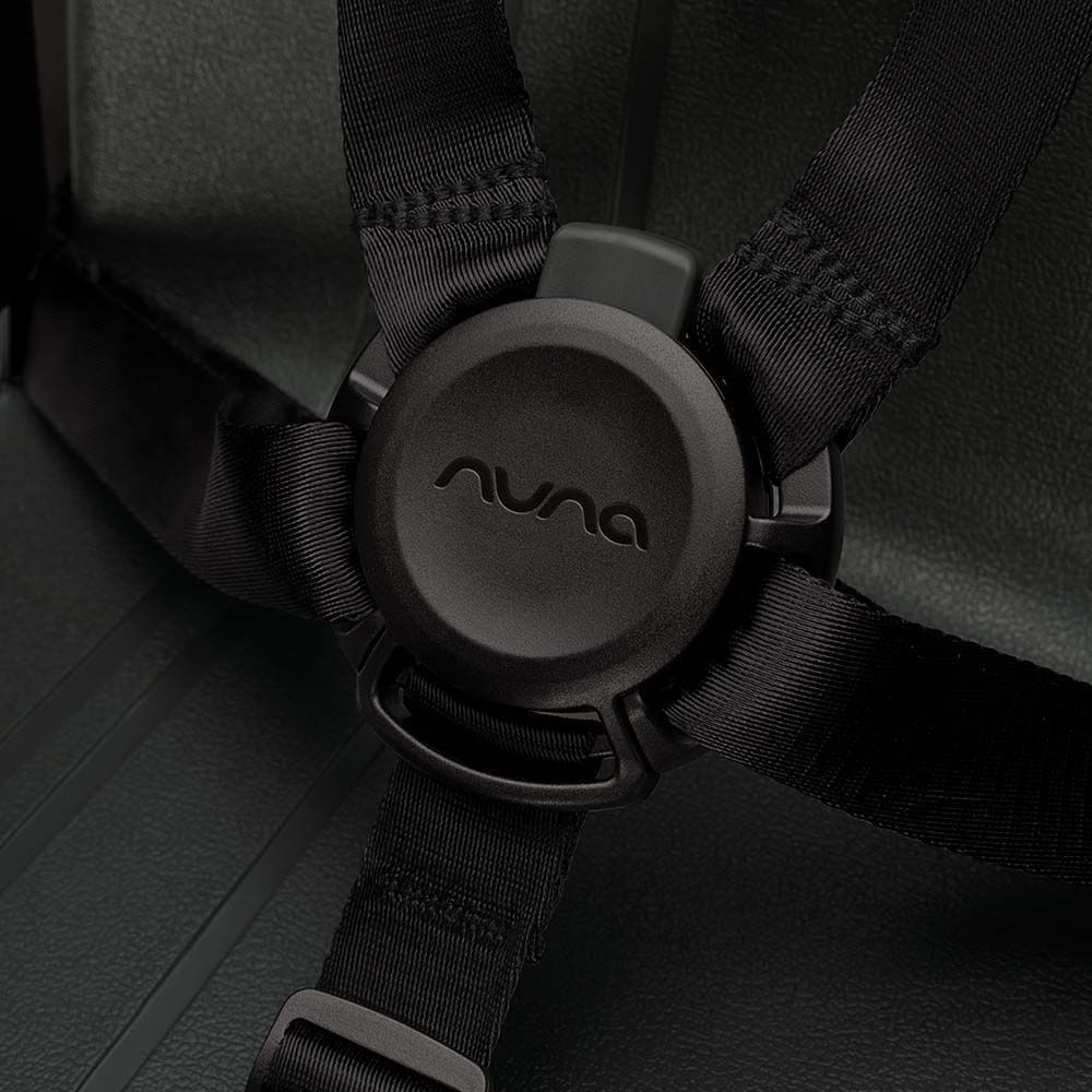 Close-up do fecho central do arnês de segurança da cadeira Nuna ZAAZ, com o logótipo Nuna gravado.