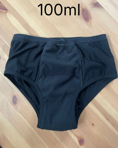Interior da cueca absorvente preta indicando capacidade de retenção de 100ml.