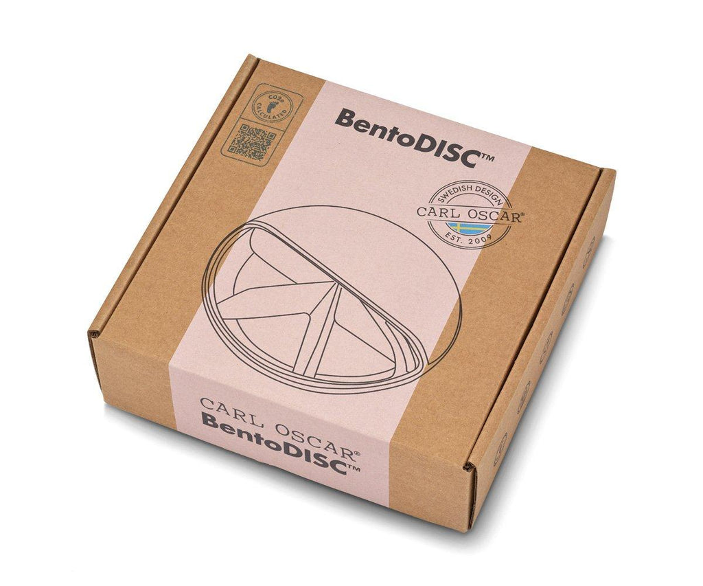 Embalagem de cartão reciclado da lancheira Carl Oscar BentoDisc, com selo de design sueco e logótipos da marca, destacando a sustentabilidade.