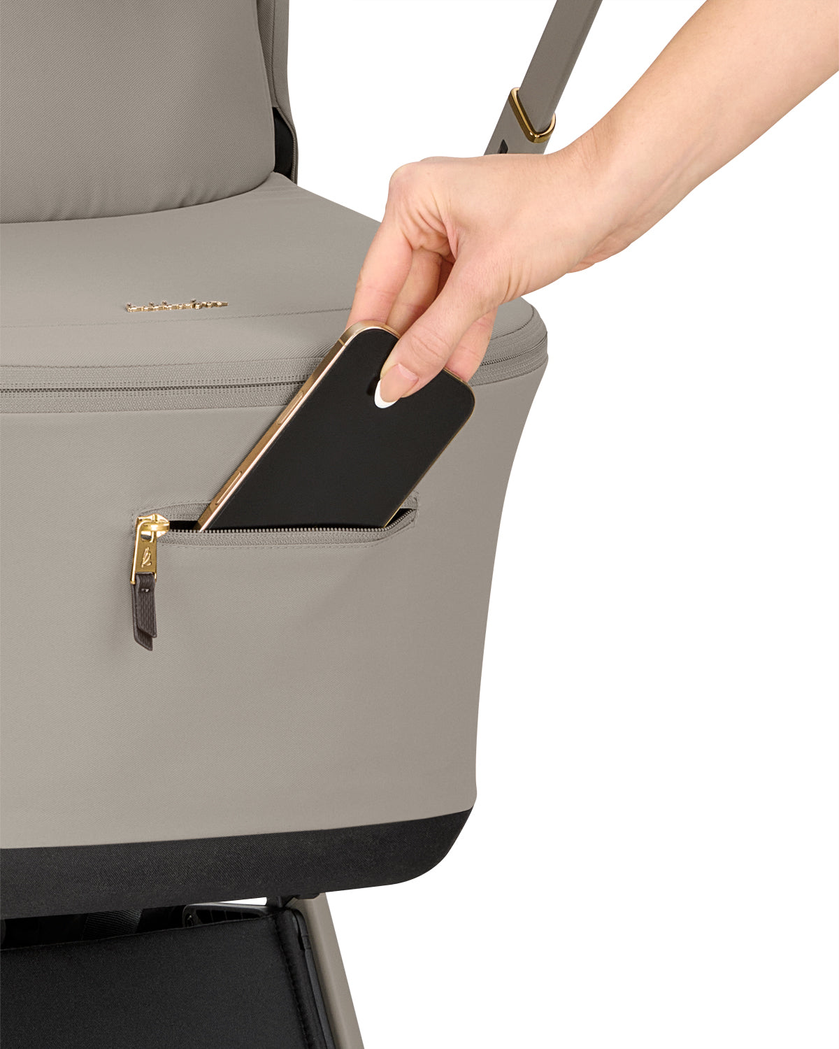 Mão a guardar um telemóvel num pequeno bolso com fecho de correr na lateral do capazo do carrinho KikkaBoo Goya Platinum.