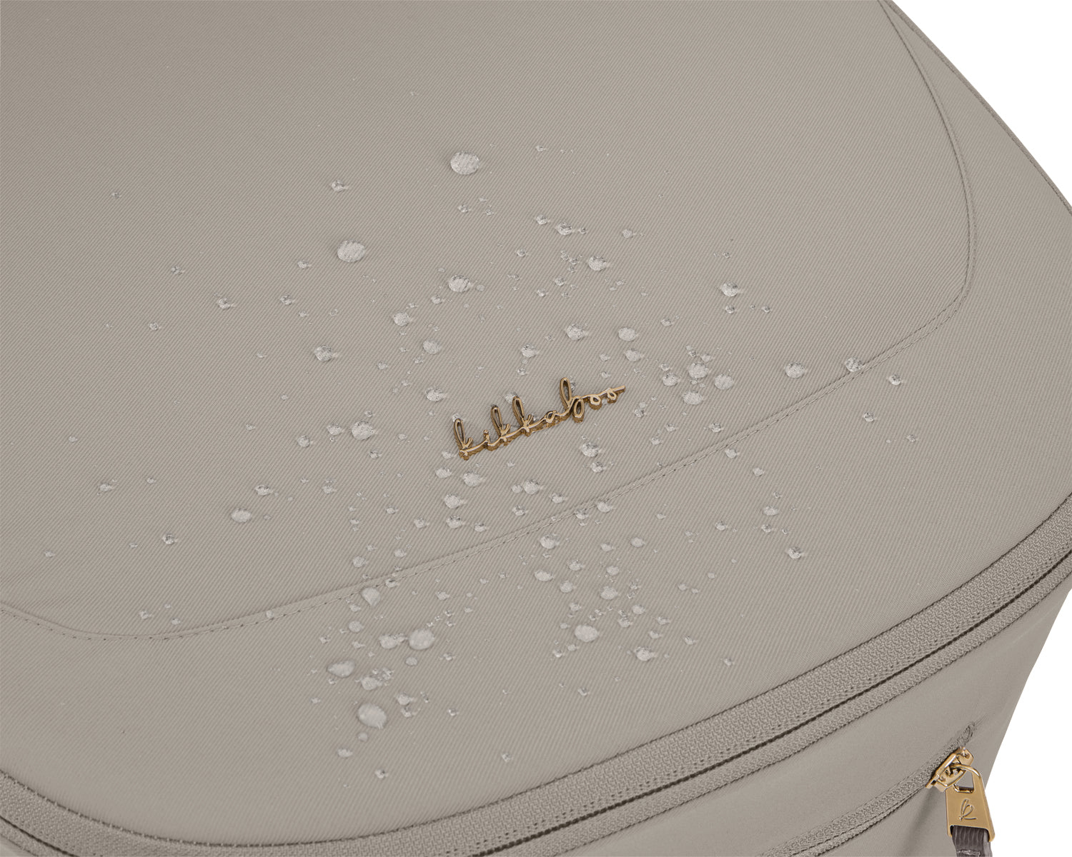 Close-up do tecido do capazo do carrinho Goya Platinum, mostrando gotas de água a escorrer devido à sua impermeabilidade, com o logótipo dourado visível.