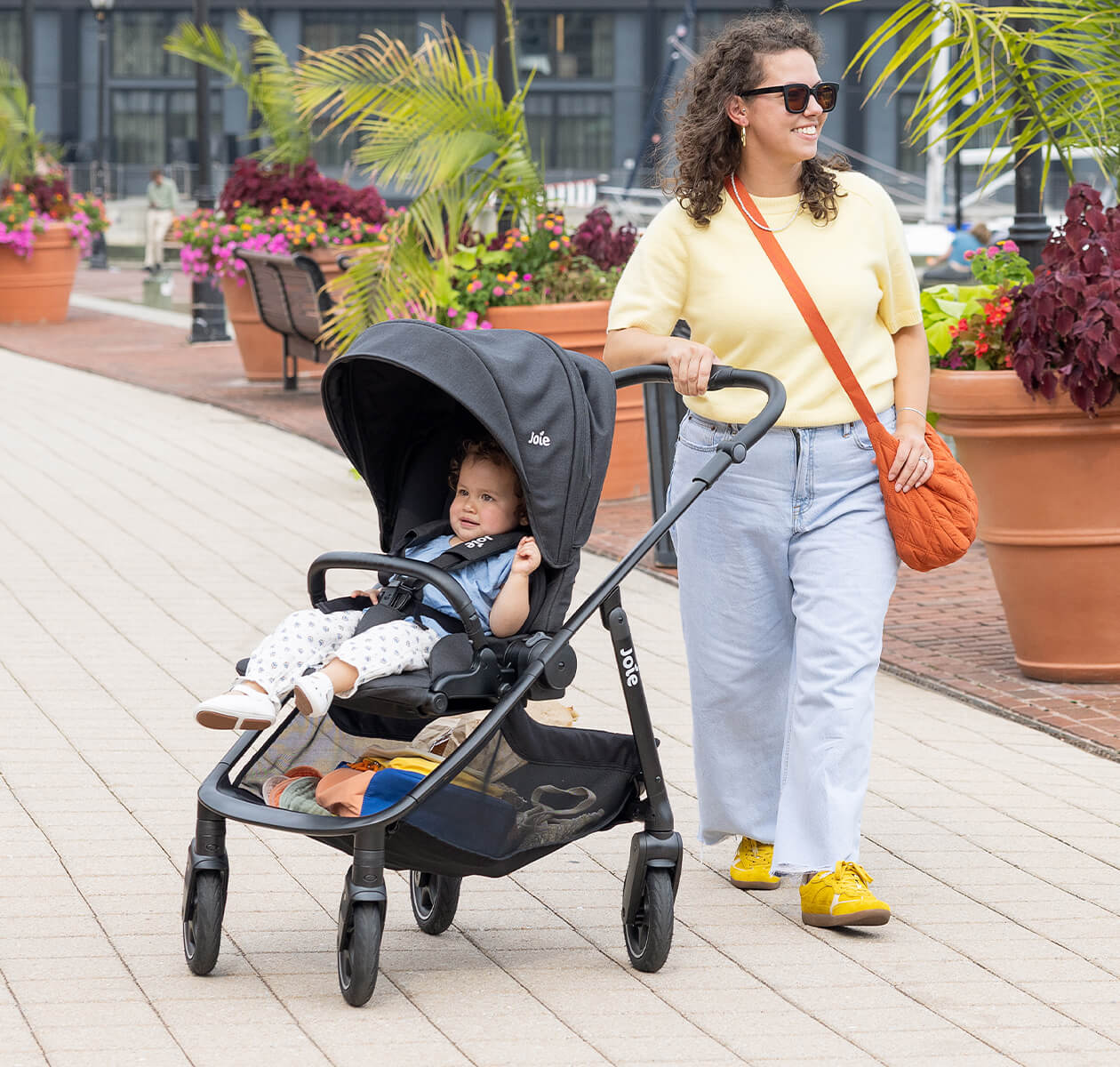 Carrinho de bebé Joie versadrift dobrado na vertical, mostrando o mecanismo compacto de fecho com uma só mão.