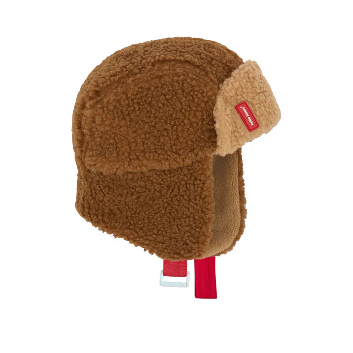 Vista lateral de um gorro aviador Hello Hossy Cozy Sven castanho claro, com forra polar e laços vermelhos, em fundo branco.