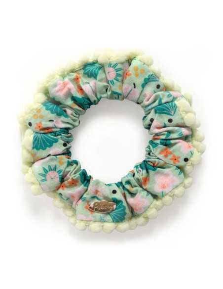Chouchou redondo da Djeco, com tecido verde-água estampado e orla exterior de pompons amarelos claros.