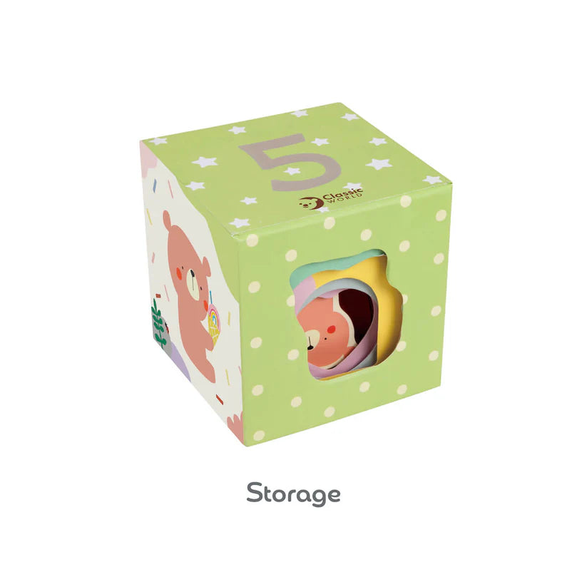 Cubo de armazenamento verde com o número 5 e estrelas, mostrando as peças de encaixe coloridas no interior através dos orifícios laterais. Etiqueta "Storage".