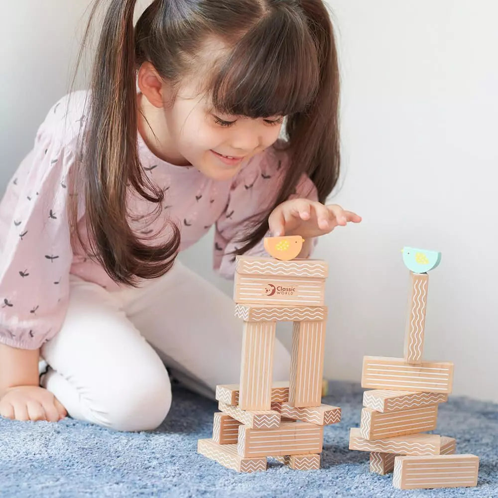 Criança concentrada a brincar com o Classic World Jogo de empilhar pássaros, explorando o equilíbrio e a construção.